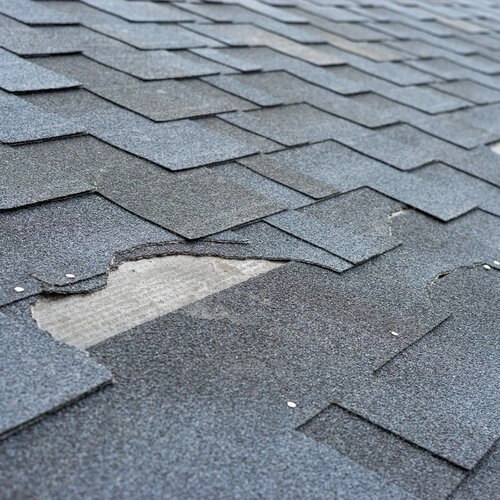 close-up of a roof with missing and damaged shingles 