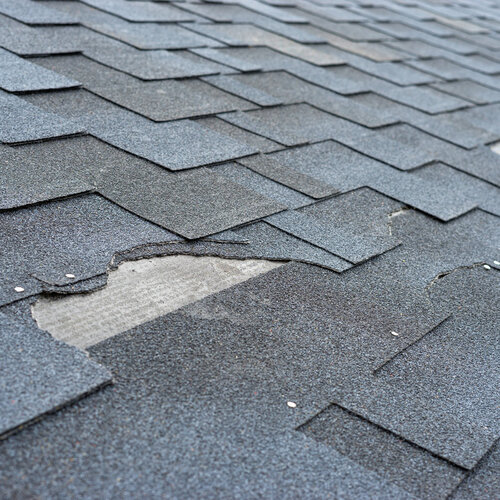 close-up of a roof with missing and damaged shingles