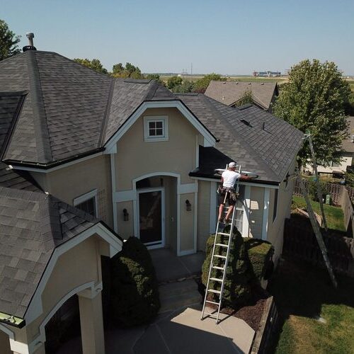 worker inspecting a home's shingle roof