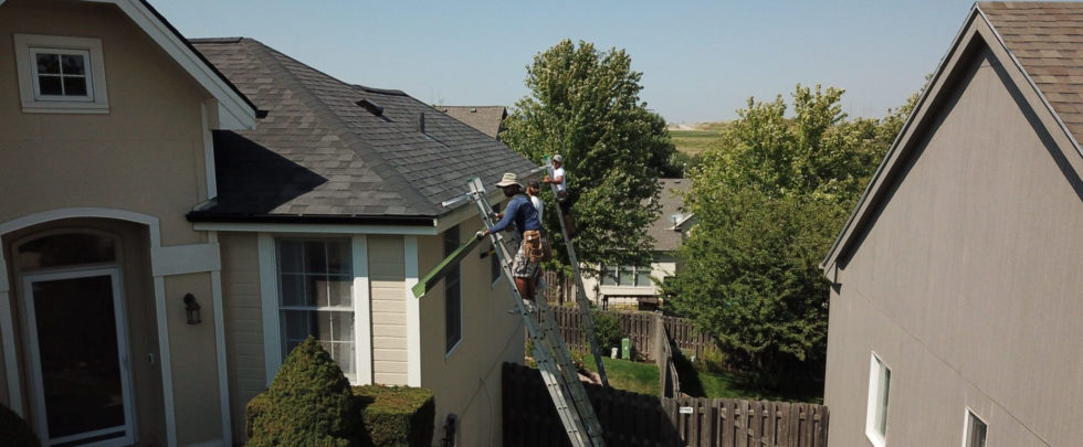 worker installing gutters on home